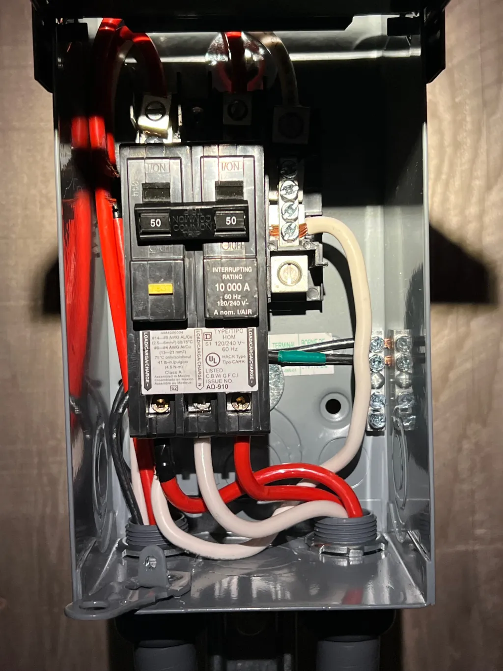 An open electrical panel box with two 50-amp circuit breakers and red, white, and black wires connected.